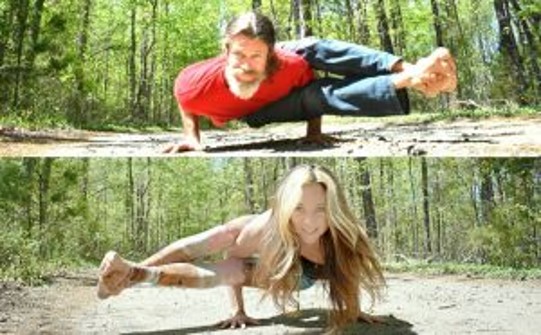 A man and woman doing yoga in the woods.